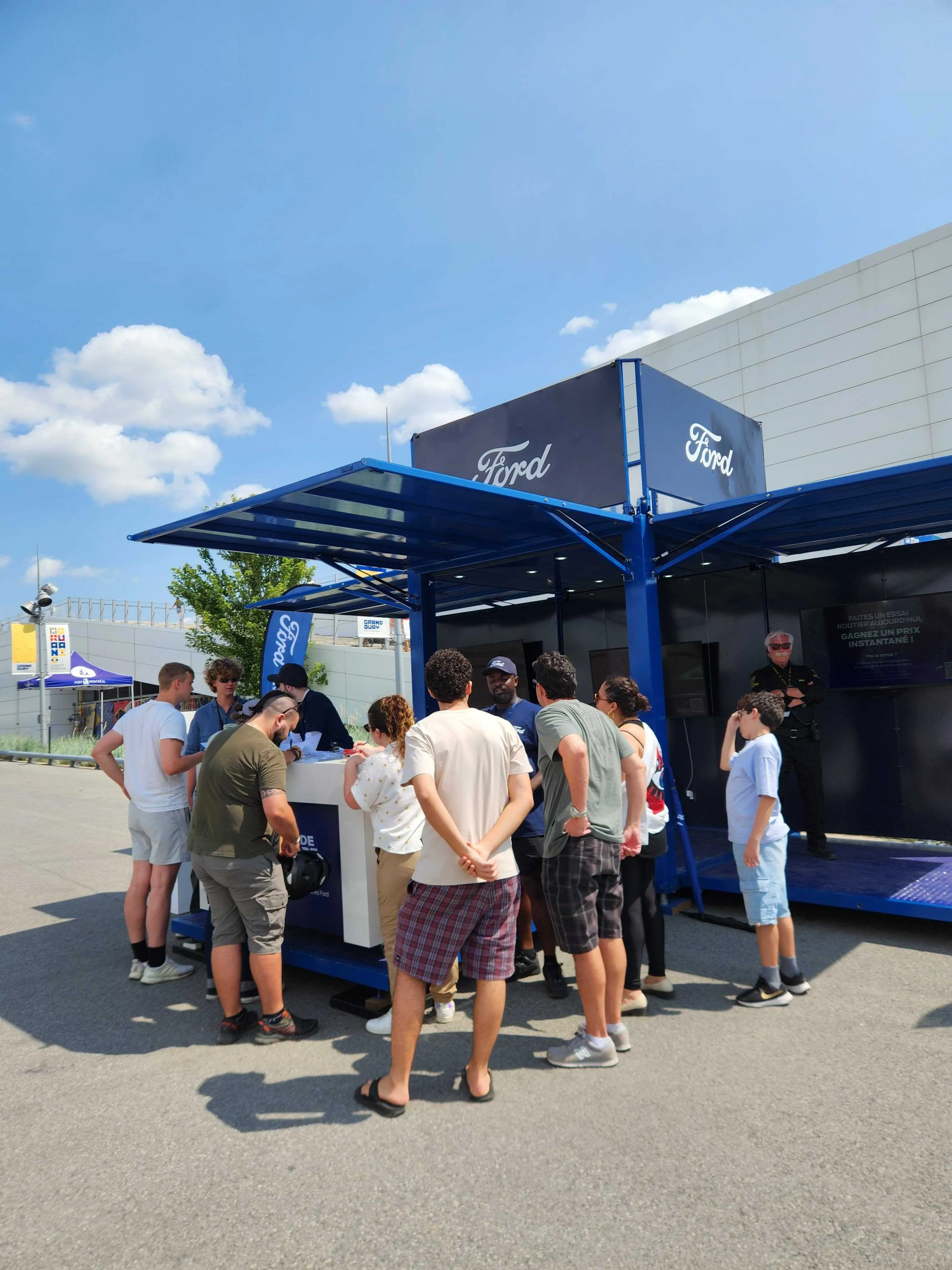 Blue Ford event booth with a queue of attendees in daylight