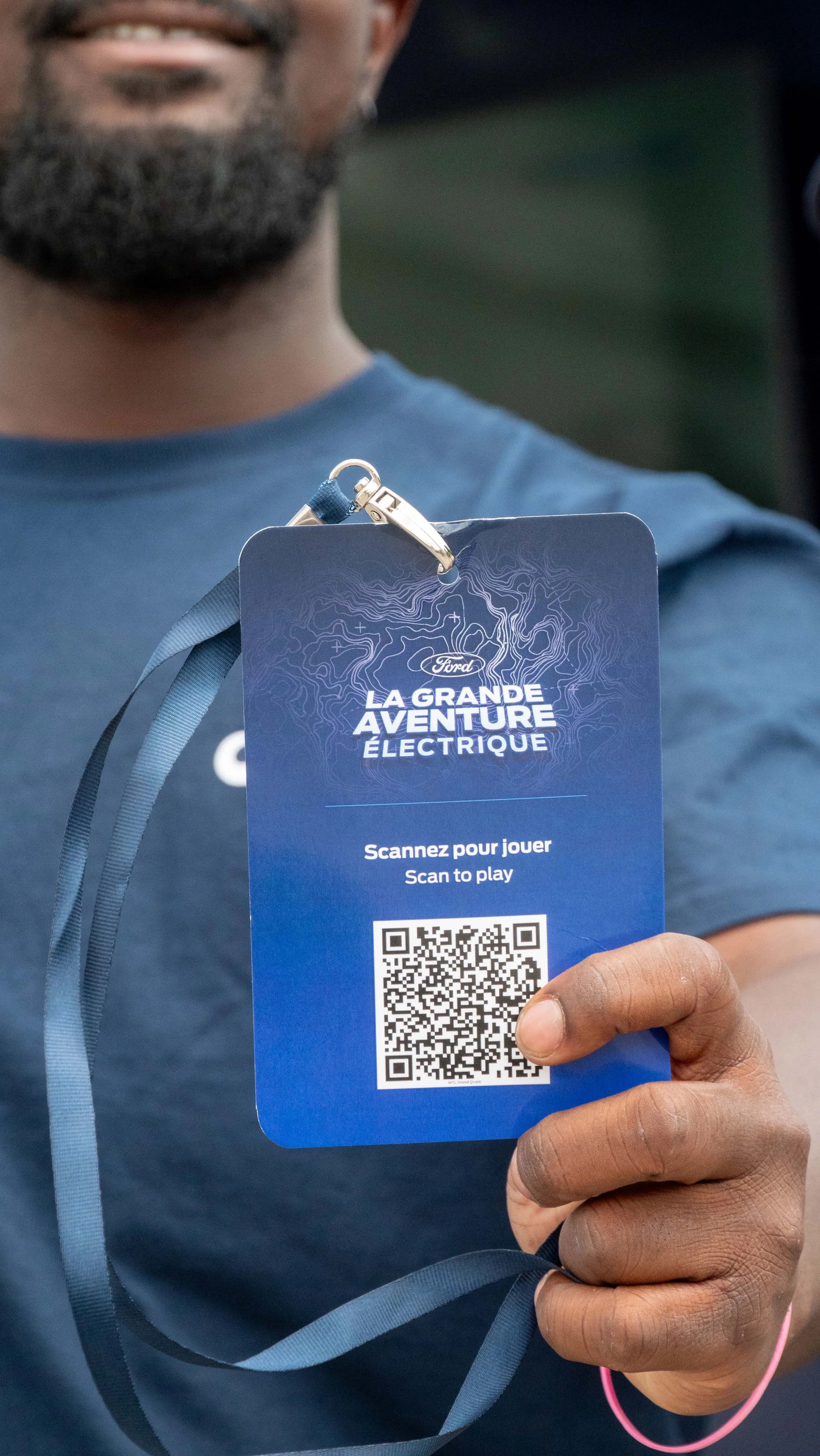 Person holding a blue event lanyard with a QR code