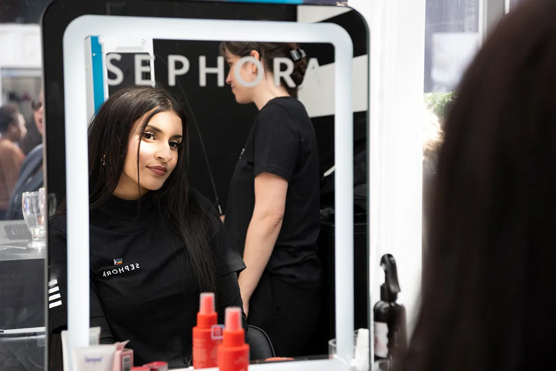 Makeup artist applying eyeshadow to a guest at the counter