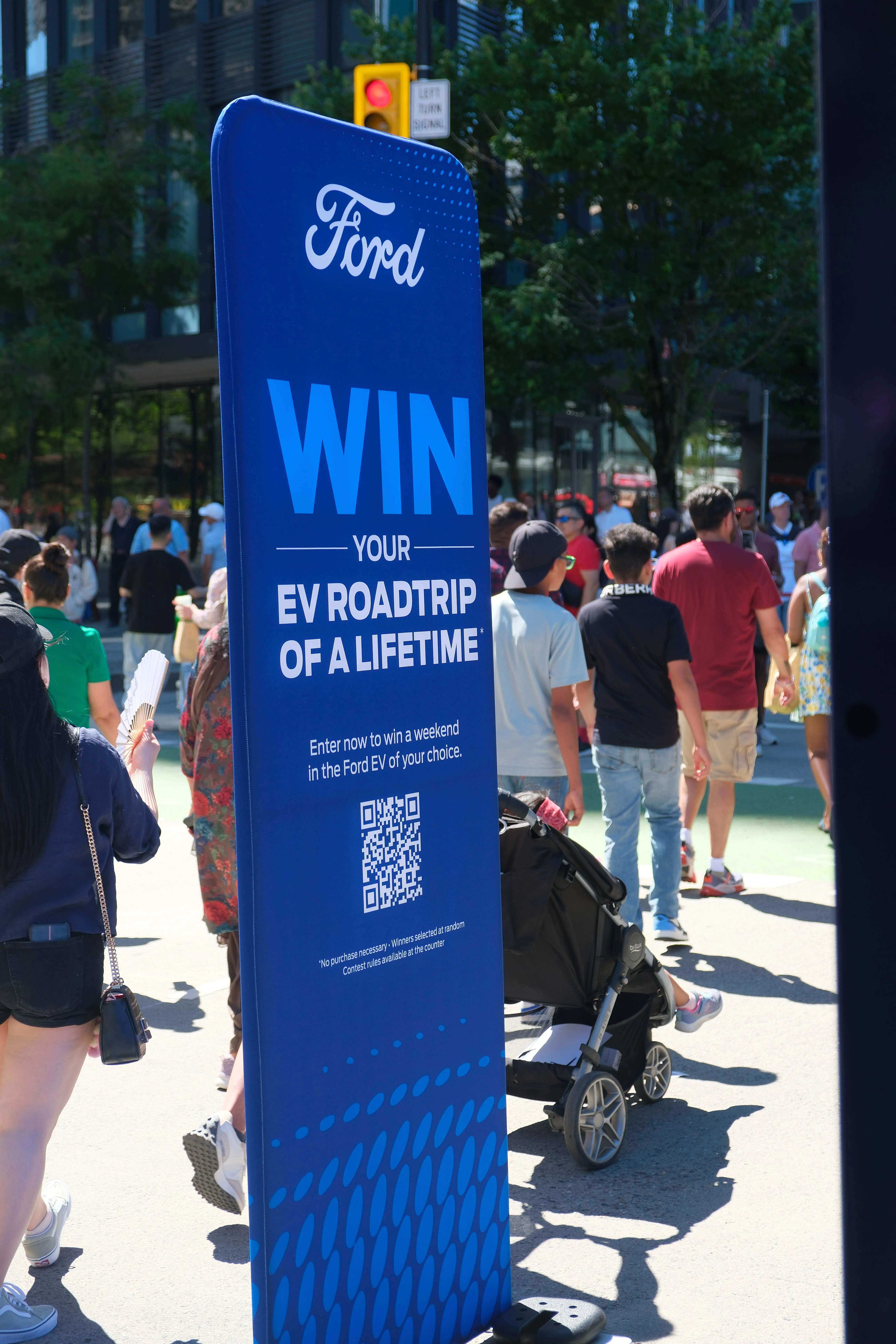 Tall blue signage in a plaza advertising the Ford EV contest