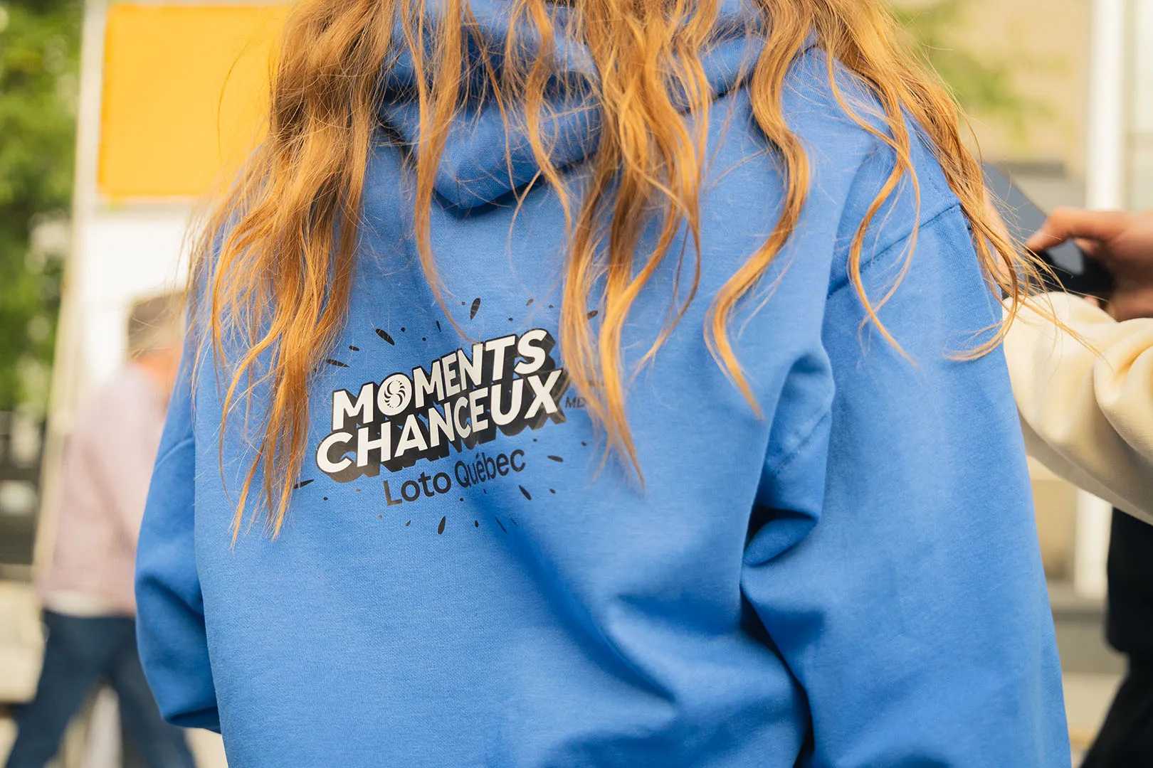 Close-up of staff member in blue Moments Chanceux hoodie with confetti scattered around