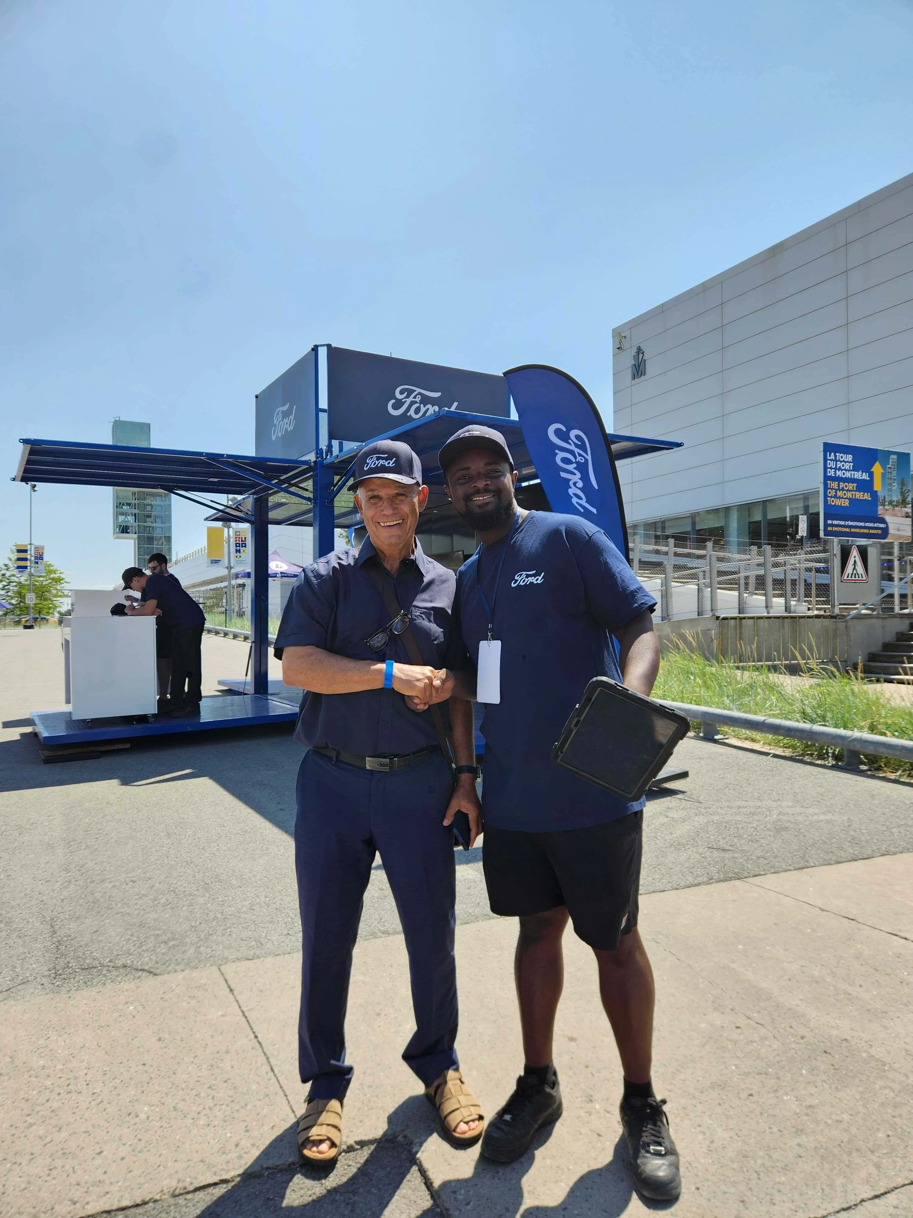 Two Ford staff in blue uniforms shaking hands outside