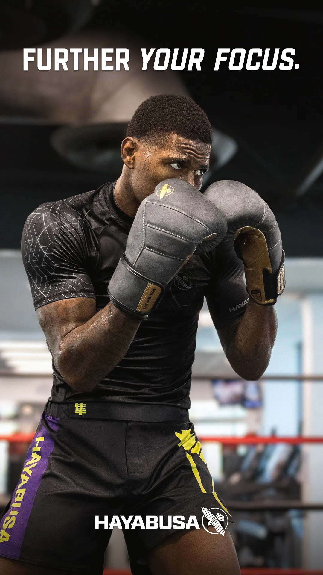 Male boxer in guard stance wearing grey and gold Hayabusa boxing gloves