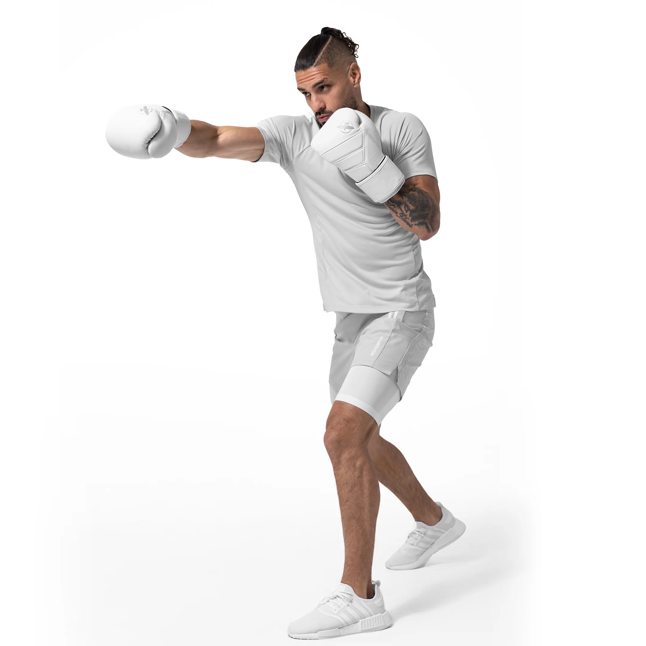 Male athlete in a white Hayabusa outfit with hand wraps in a punching stance