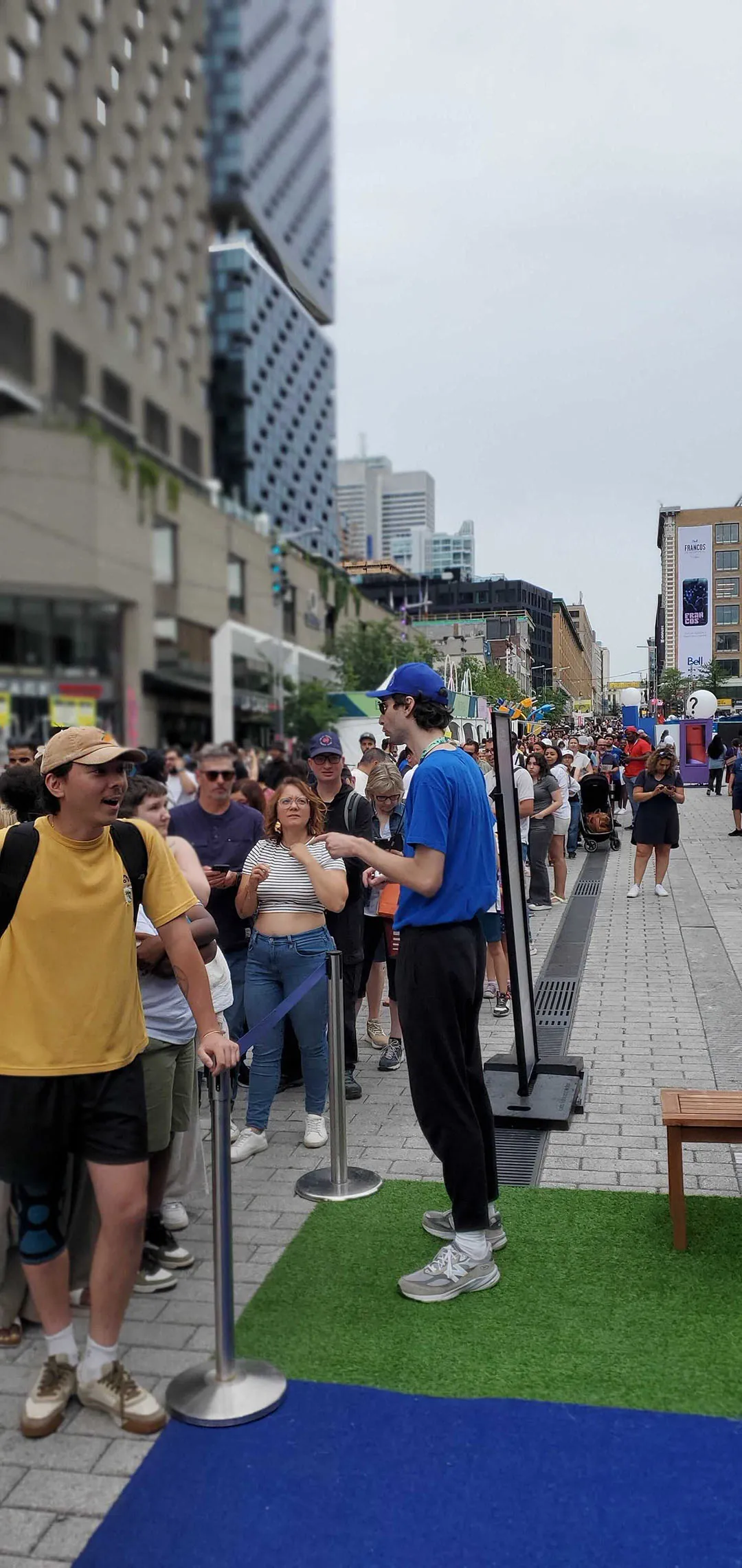 Street festival plaza with staff in blue interacting with crowds and artificial grass flooring