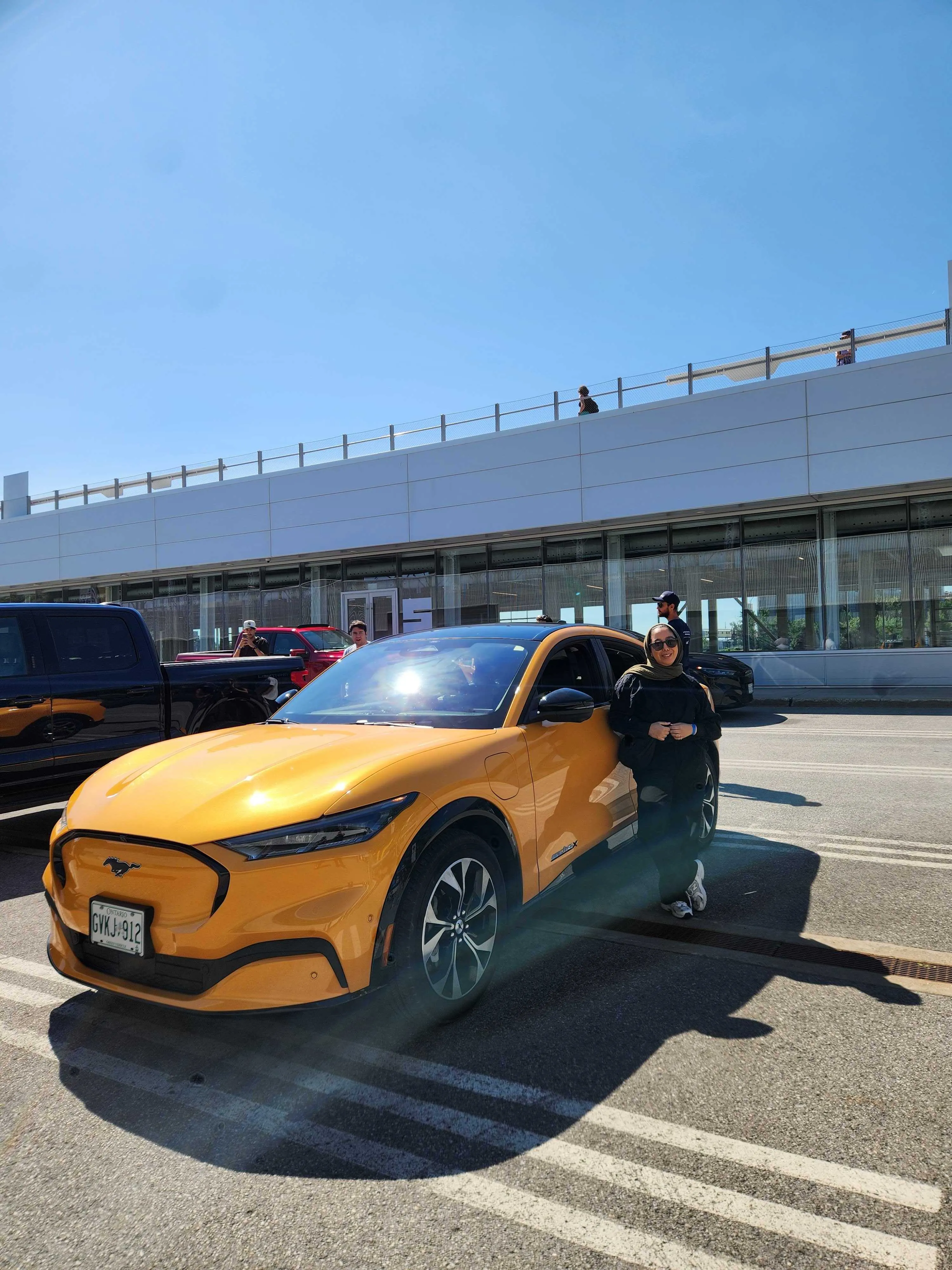 Yellow Ford Mustang Mach-E with woman standing beside it