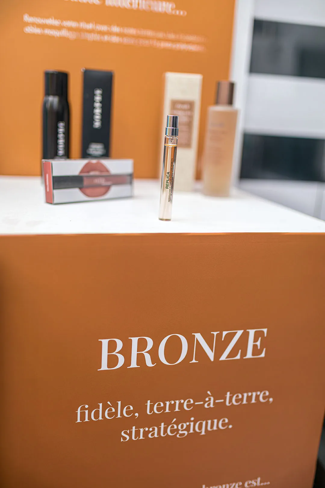 Cosmetic products and brushes on an orange backdrop