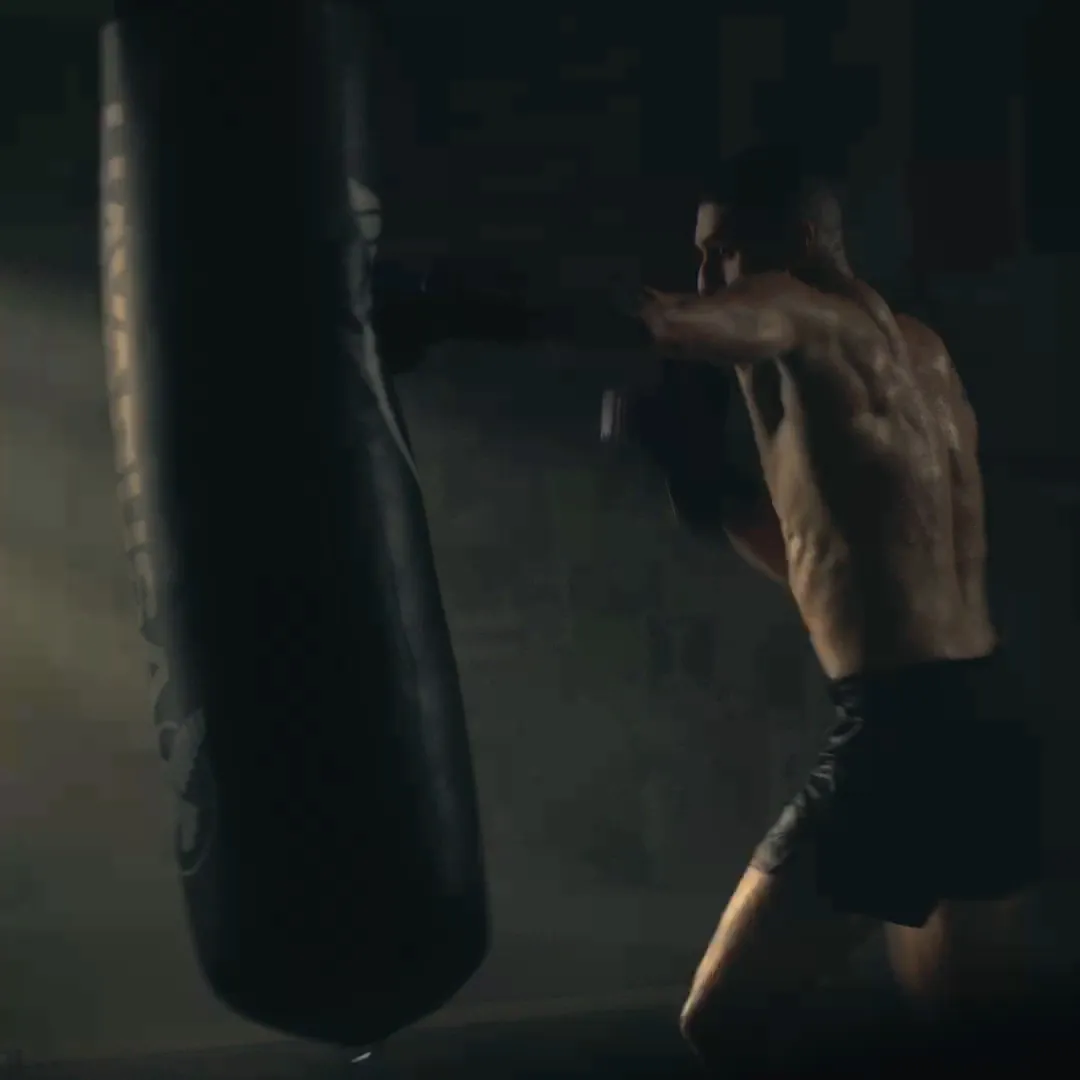 Male athlete punching a heavy bag in a low-light training session