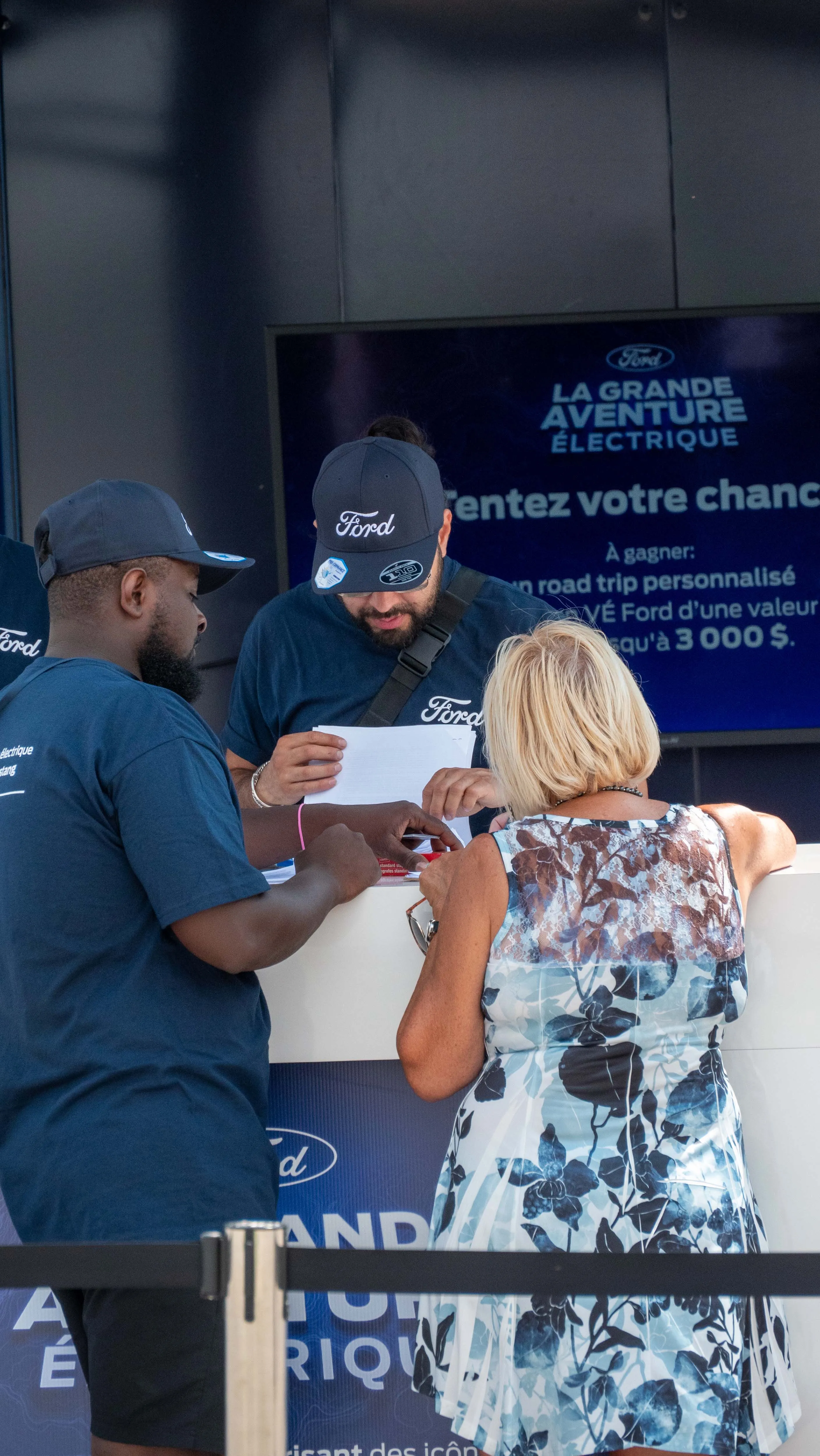 Ford staff helping visitor complete contest entry at booth counter