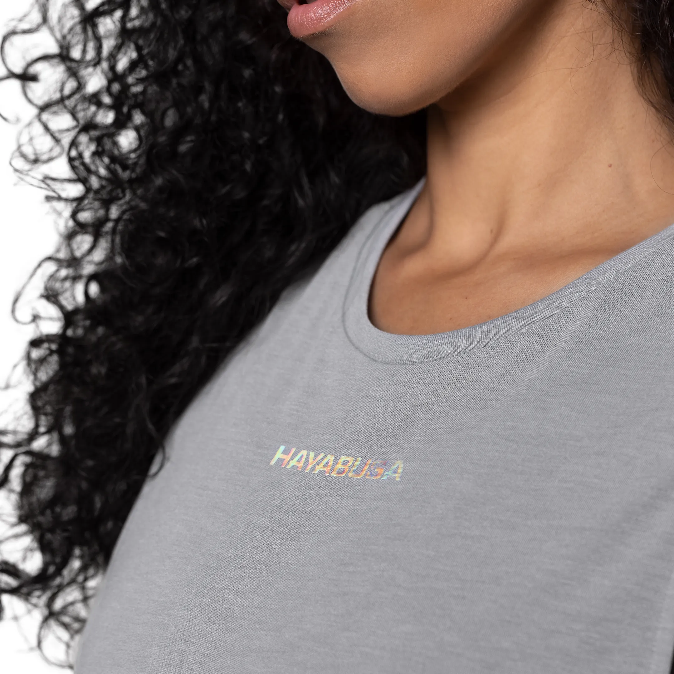 Woman in a grey Hayabusa tee with an iridescent logo, close portrait