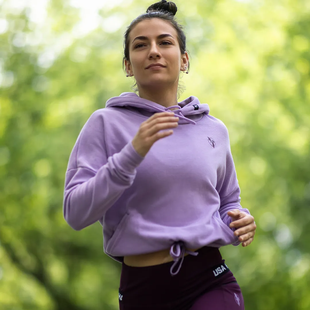 Woman jogging in a lavender Hayabusa cropped hoodie in a green park