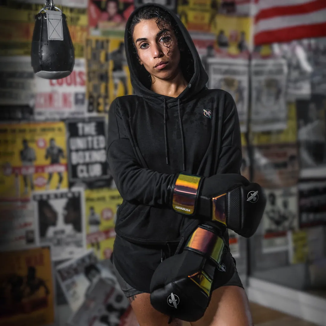 Female athlete in black Hayabusa hoodie with black and orange gloves in gym