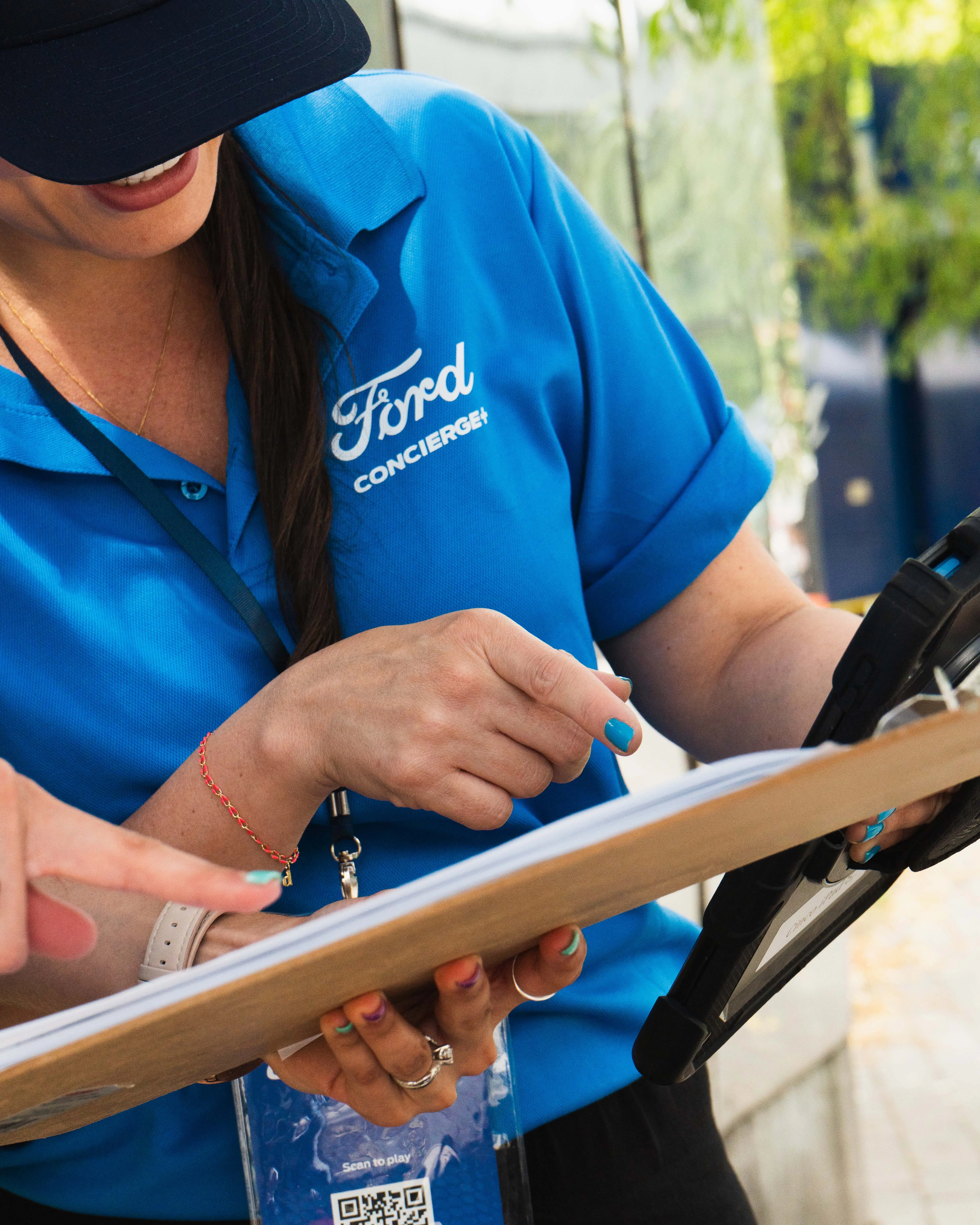 Ford staff member in blue polo holding QR scan tablet at activation booth