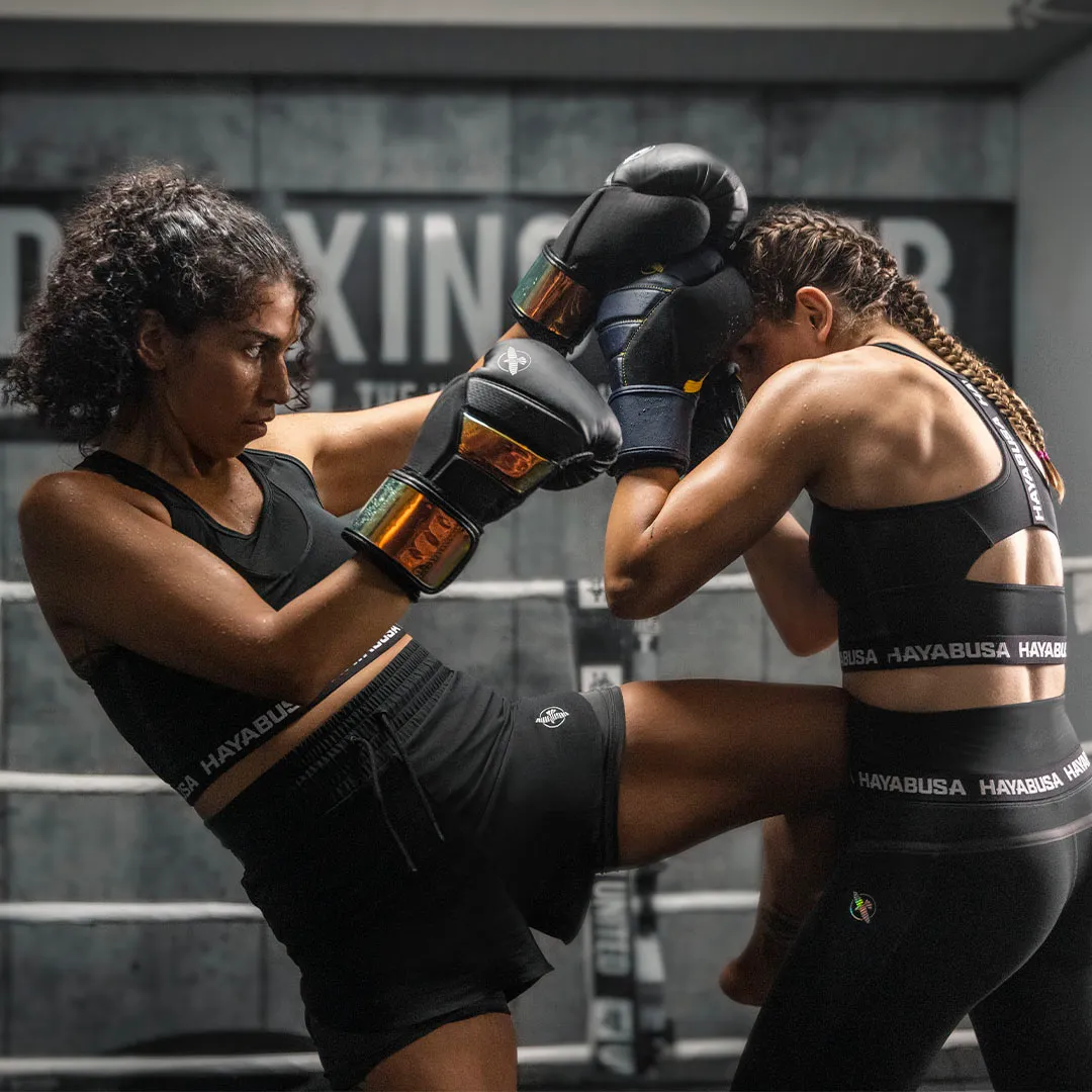 Two female boxers sparring in black Hayabusa apparel with orange accents