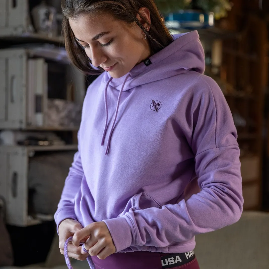 Woman in a lavender Hayabusa hoodie, hands in pockets, in an urban warehouse setting