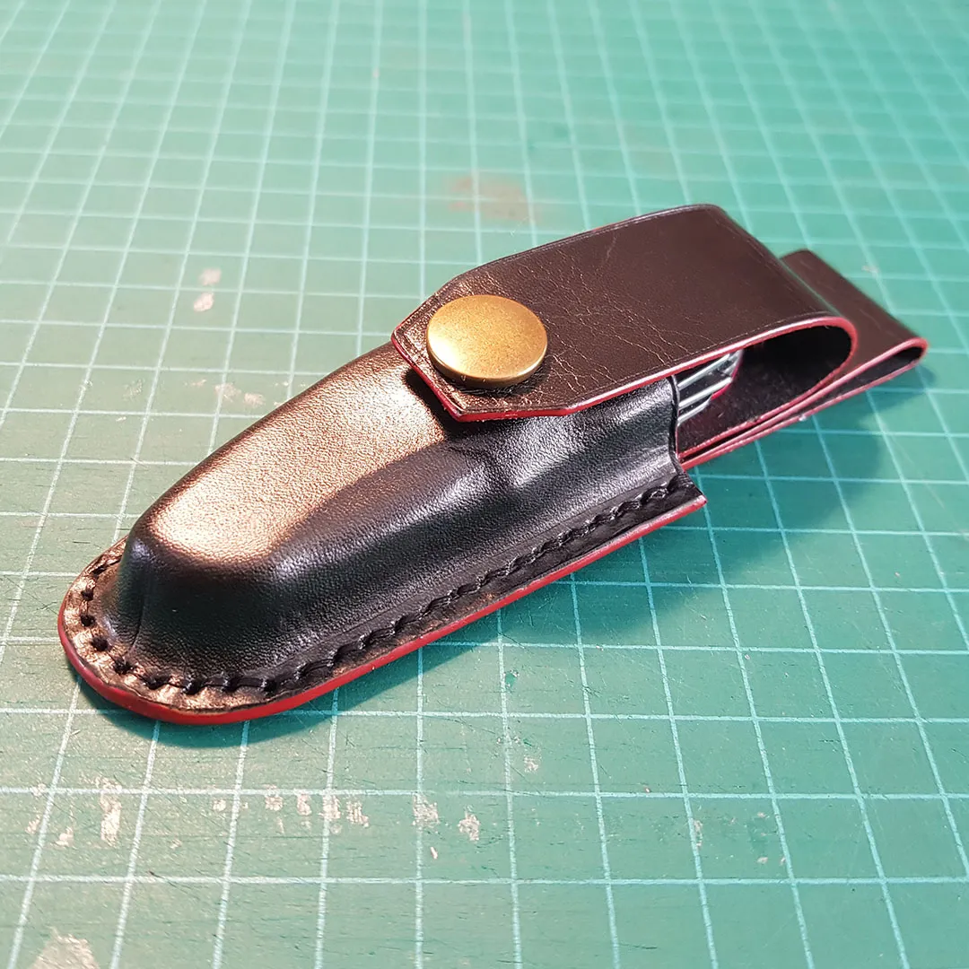 Finished black knife sheath with a brass snap and belt loop