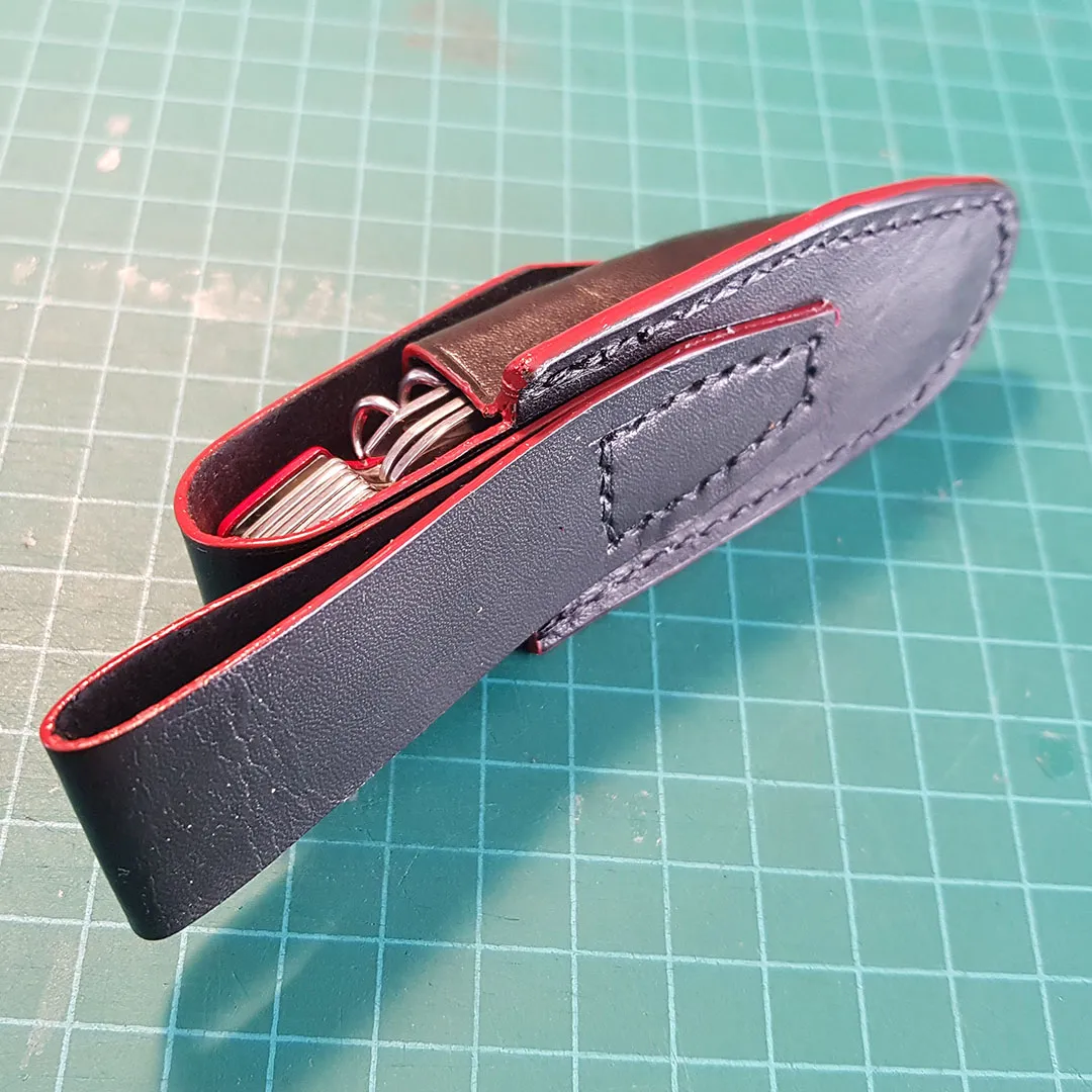 Side view of the sheath with red edge coat and a folding knife inside