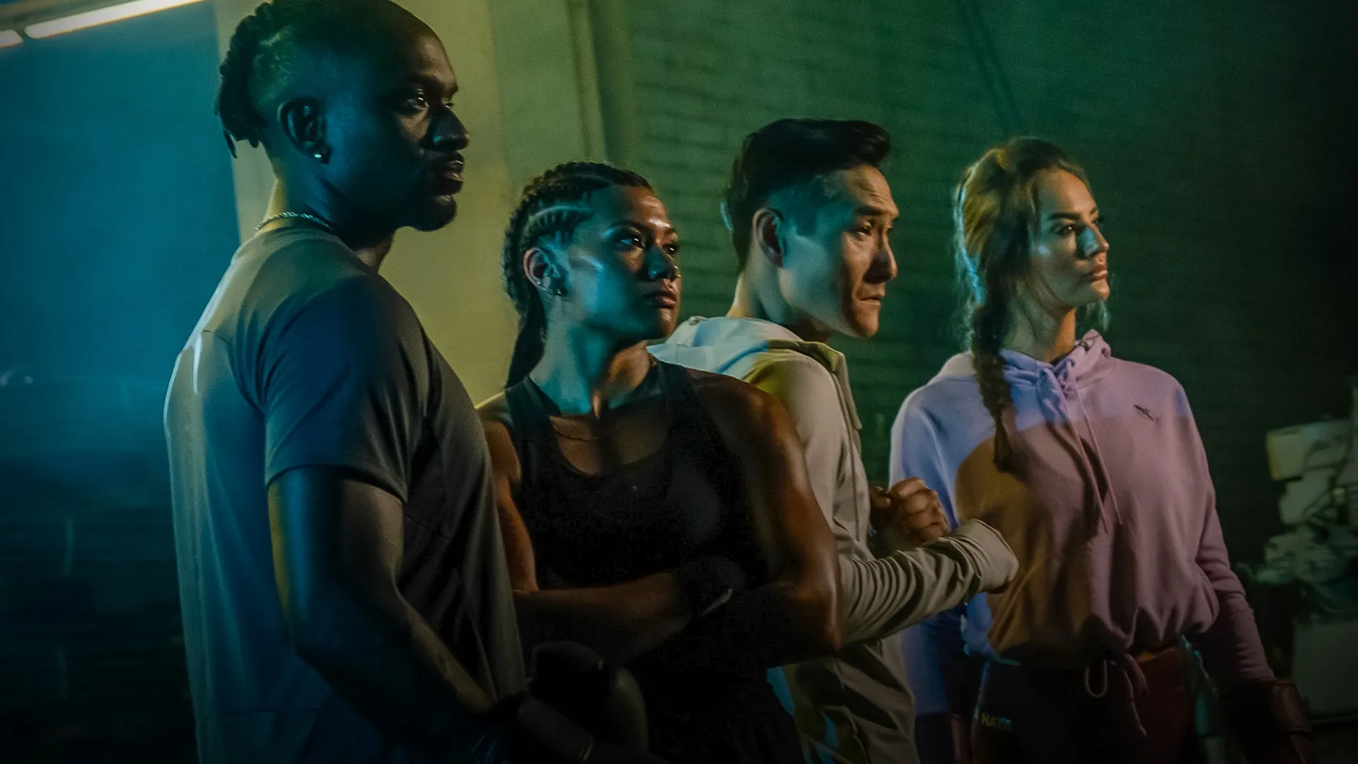 Four athletes in Hayabusa apparel under moody blue-green and amber lighting